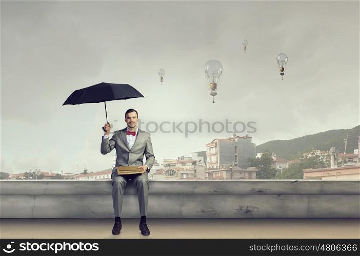 Businessman reading old book. Young businessman reading book sitting on roof of building