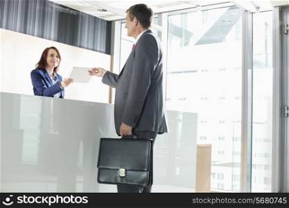 Businessman receiving document from receptionist in office
