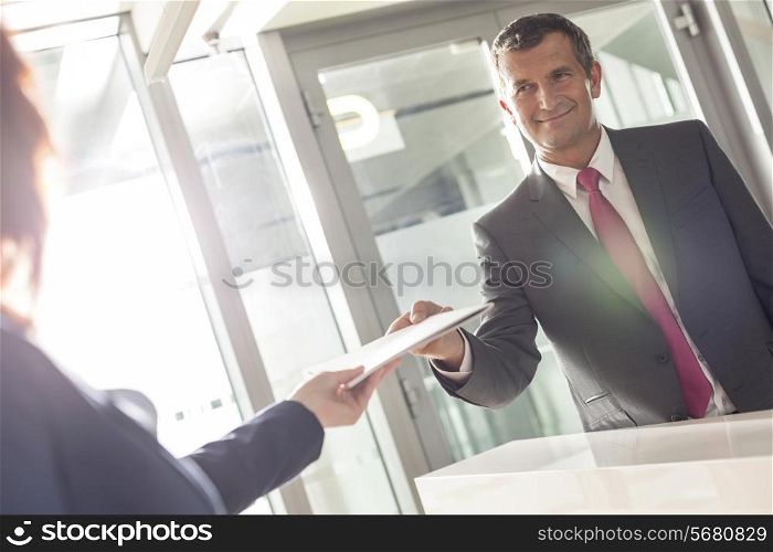 Businessman receiving document from receptionist in office
