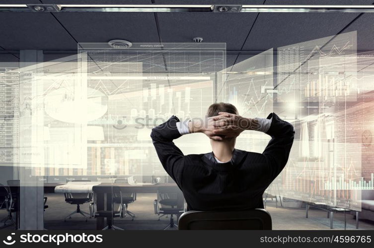 Businessman relaxing in his office mixed media. Relaxed businessman at the office sitting back with his hands behind his head