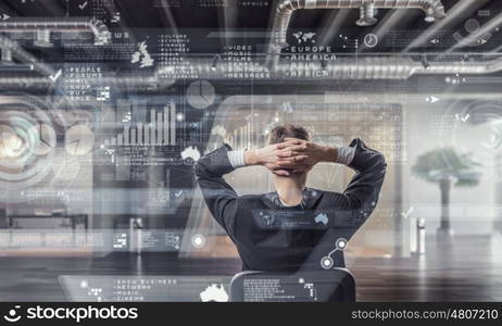 Businessman relaxing in his office mixed media. Relaxed businessman at the office sitting back with his hands behind his head