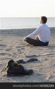 Businessman relaxing on beach - Focus on the shoes in the foreground