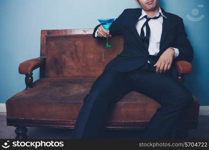 Businessman relaxing on sofa with cocktail