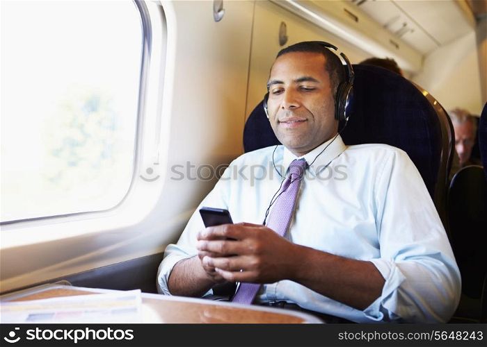 Businessman Relaxing On Train Listening To Music