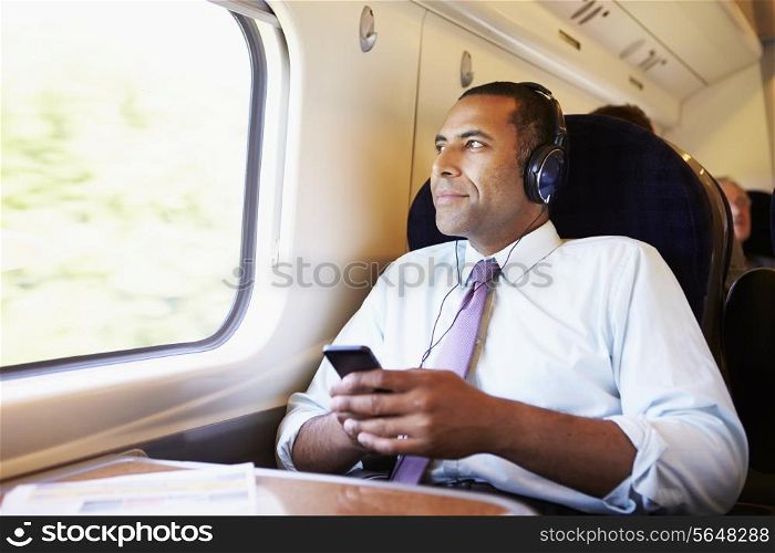 Businessman Relaxing On Train Listening To Music