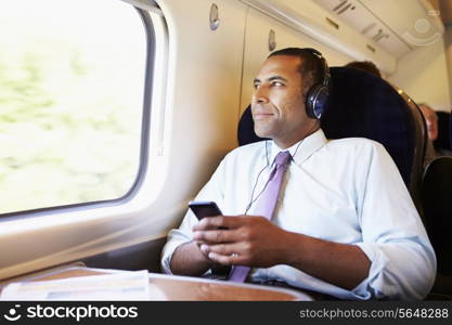 Businessman Relaxing On Train Listening To Music