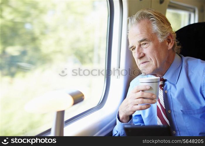 Businessman Relaxing On Train With Cup Of Coffee