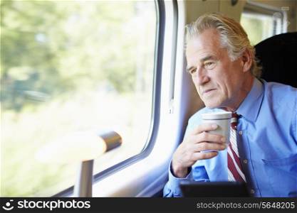 Businessman Relaxing On Train With Cup Of Coffee