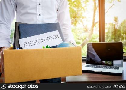 Businessman resignation packing up all his personal belongings and files into a brown cardboard box