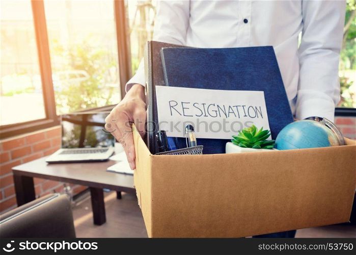 Businessman resignation packing up all his personal belongings and files into a brown cardboard box