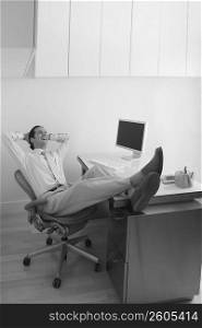 Businessman resting his legs on the desk and laughing in an office