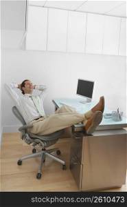 Businessman resting his legs on the desk and laughing in an office