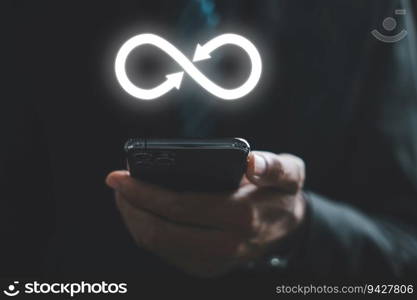 Businessman reveals smartphone with infinity symbol, representing unlimited connection in data technology. Cyber space, future unlimited. Infinite power, internet information. technology infinity data