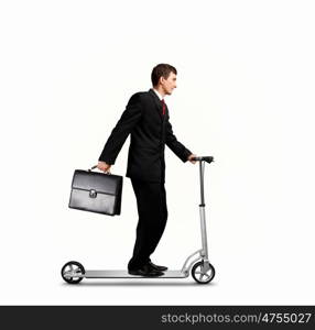 Businessman riding scooter. Image of young businessman in black suit riding scooter