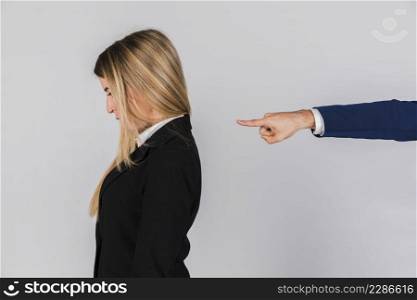 businessman s hand blaming young businesswoman against grey backdrop 