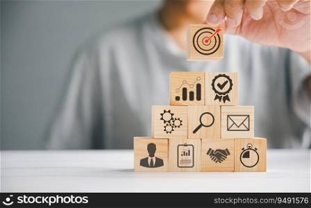 Businessman’s hand stacking wooden blocks on a table, highlighting the importance of a business strategy and action plan. Conceptual image of business development. Copy space provided.
