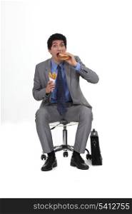 Businessman sat eating burger and French fries