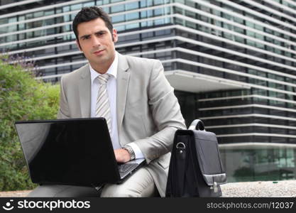 Businessman sat outside with laptop computer