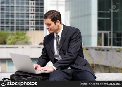 Businessman sat using laptop in the city