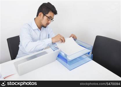 Businessman searching documents at desk in office