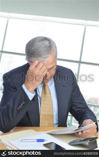 Businessman Seated at His Desk in Modern Office Setting Reading Newspaper