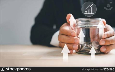 Businessman securing passive income via real estate investment. Future wealth strategy with property, house value, and financial success. Banking on growth, currency, economy, insurance.. Hands of adults holding money jar with house icon