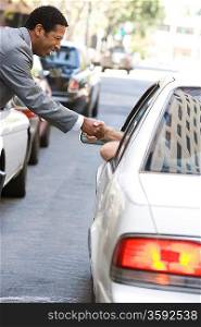 Businessman shaking hand with car driver