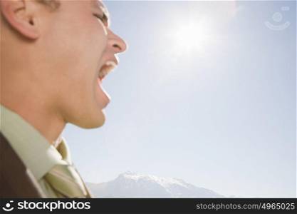 Businessman shouting by mountains