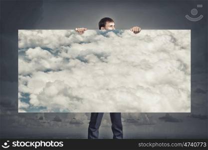 Businessman showing banner. Young businessman holding banner with blue cloudy sky