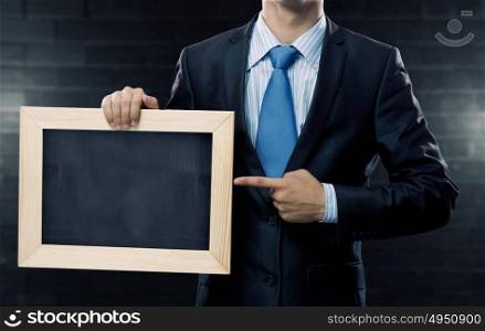 Businessman showing chalkboard. Unrecognizable businessman holding blank chalkboard. Place your text