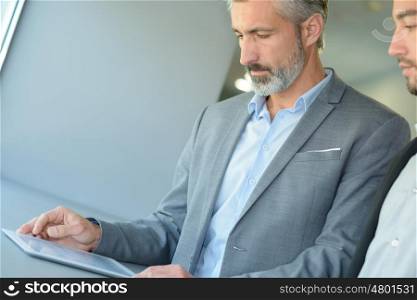 businessman showing his colleague info in a tablet