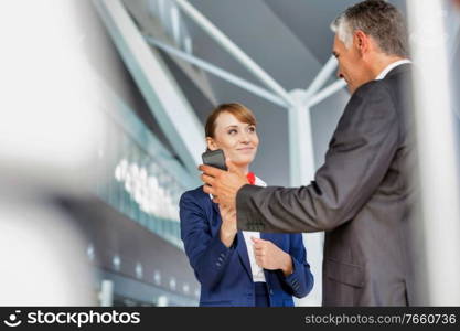 Businessman showing his electronic ticket on smartphone to passenger service agent in airport