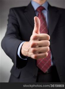 Businessman showing thumbs up sign. Neutral background
