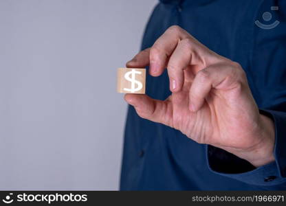 Businessman shows a wooden cube with dollar symbol. Business finance concept.. Businessman shows a wooden cube with dollar symbol.