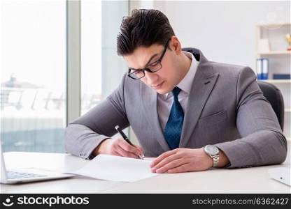 Businessman signing business documents in office. The businessman signing business documents in office