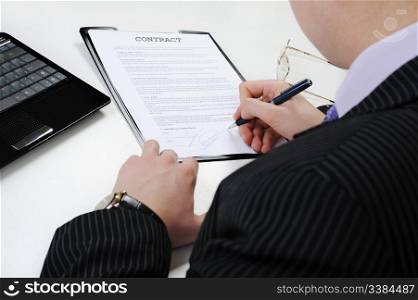 Businessman signs a contract at the table in the office