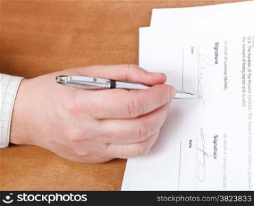 businessman signs a contract by silver pen on table