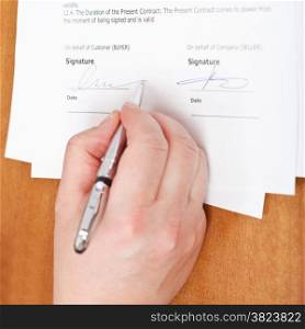 businessman signs an agreement by silver pen on table