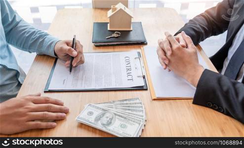 Businessman signs contract behind home architectural model Discussion with a real estate agent rental company staff at the office property appraisal and valuation concept