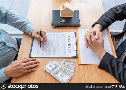 Businessman signs contract behind home architectural model Discussion with a real estate agent rental company staff at the office property appraisal and valuation concept