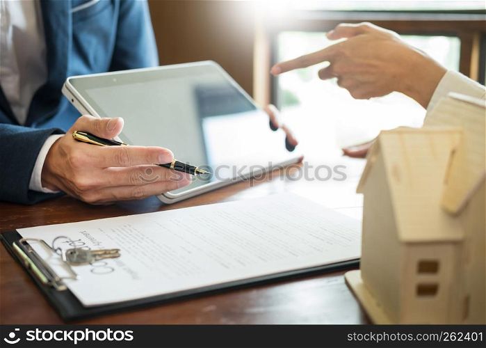 Businessman signs contract behind home architectural modelDiscussion with a real estate agent rental company staffat the office property appraisal and valuation concept