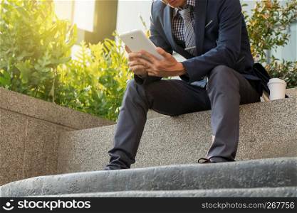 businessman sit and using tablet about data resource outdoor with coffee
