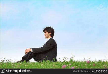 businessman sits on grass, view in profile