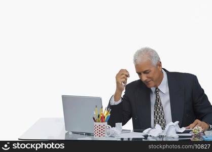 Businessman sitting at a desk with crumpled paper on the desk