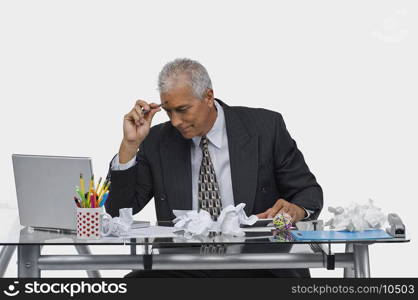 Businessman sitting at a desk with crumpled papers on the desk