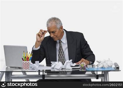 Businessman sitting at a desk with crumpled papers on the desk