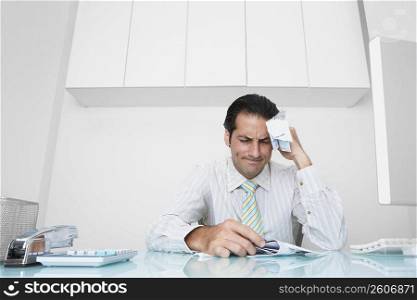 Businessman sitting at a desk with documents and looking pensive