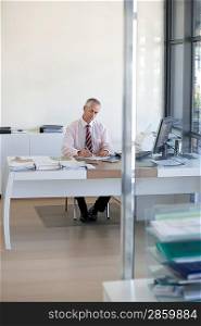 Businessman sitting at desk in office working.