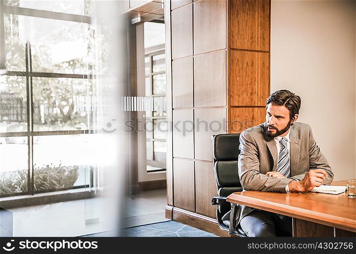 Businessman sitting at desk looking away
