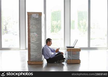 Businessman Sitting Between Two Packages Using Cell Phone